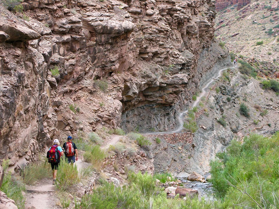 Through the Canyon Two hikers descend down the North Kaibab Trail along Bright Angel Creek