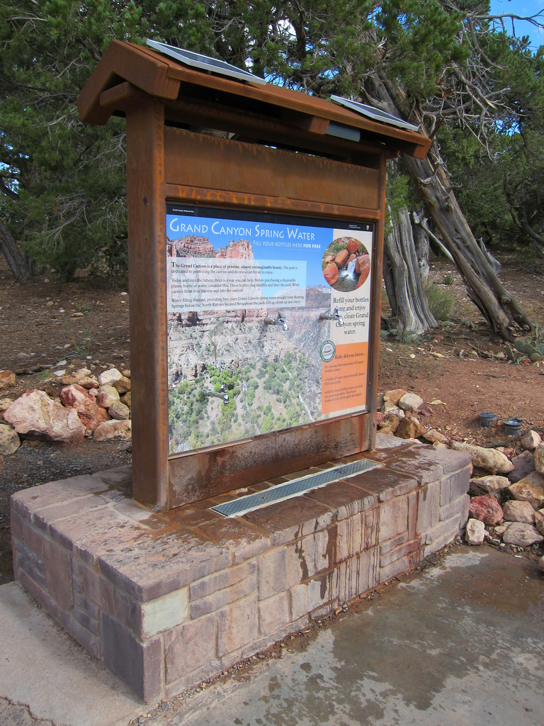 water bottle filling station built on rock; juniper trees in background