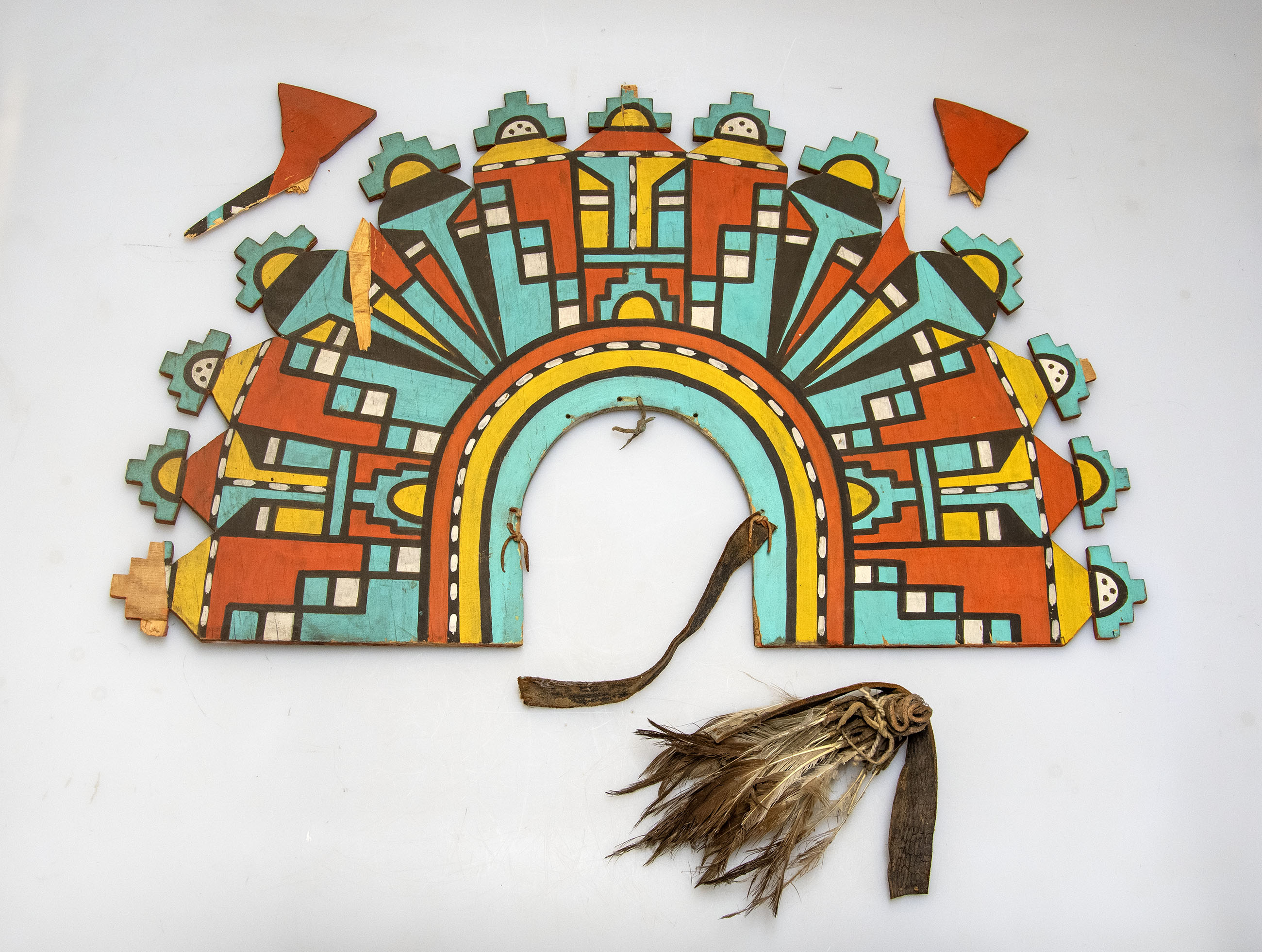 Headpiece with colorful geometric designs in red, blue, yellow, and black. Several pieces are broken off alongside it.