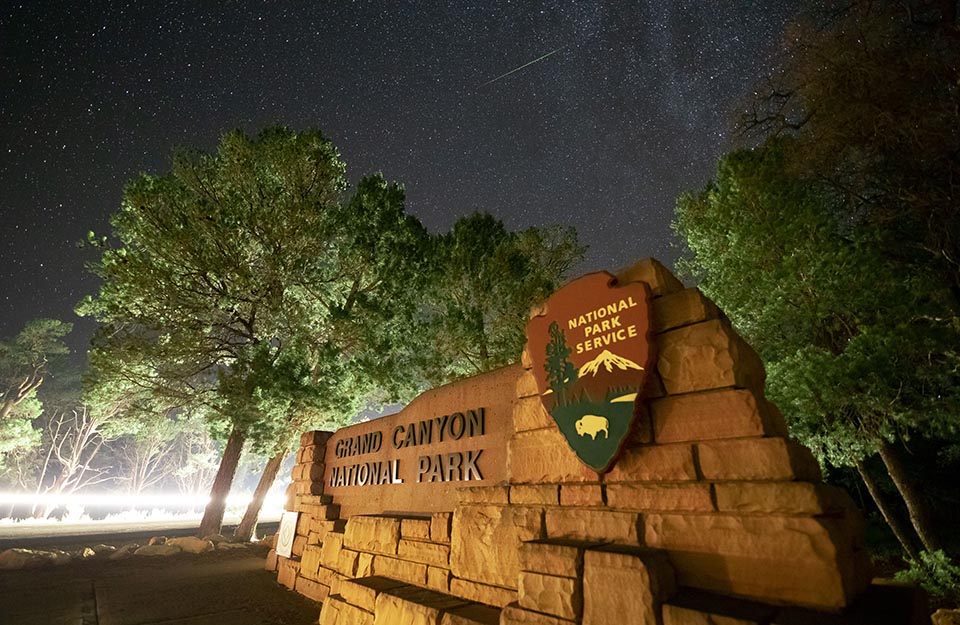 Grand Canyon National Park front entrance sign with a starry sky.