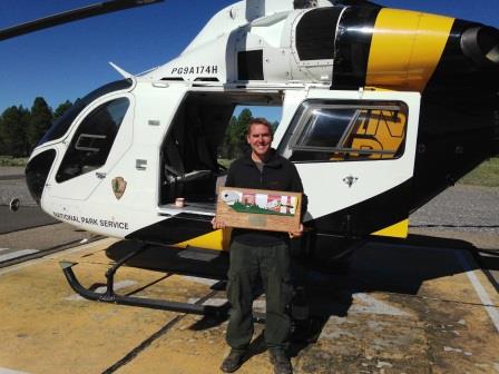 Eric Graff stands with his award in front of the park's helicopter