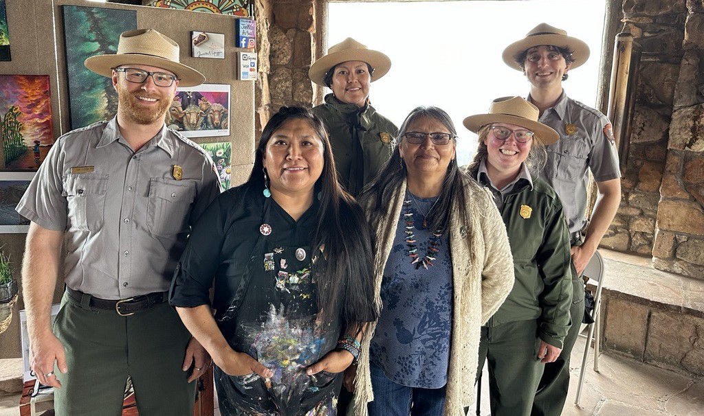 four uniformed park rangers with two Native American artists, all smiling