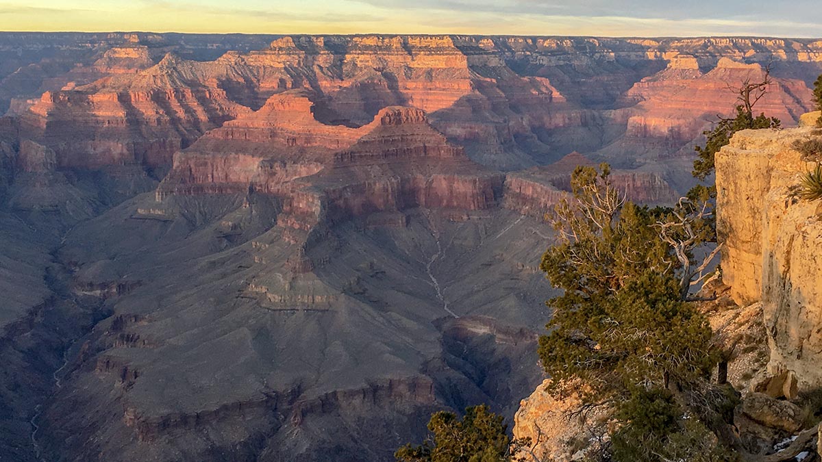 The last light of sunset falling on the tops of cliffs and peaks within a mile-deep canyon.