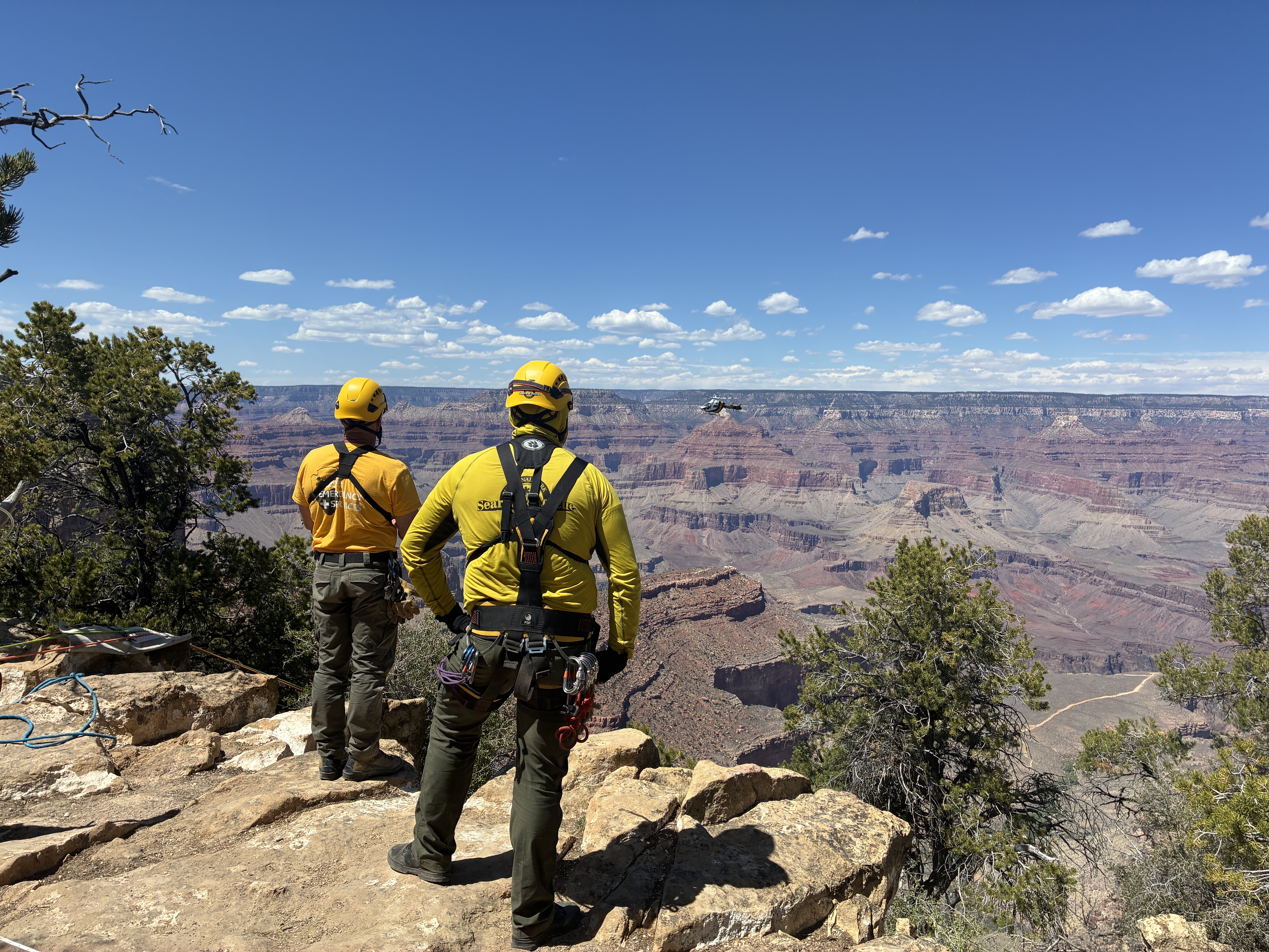 Two men in yellow technical rescue gear stand at the edge of the rim
