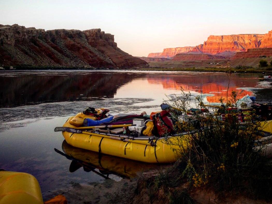 Lees Ferry launch down the Colorado River Two yellow boats with gear are parked on the shoreline of a river with pink cliffs in the background