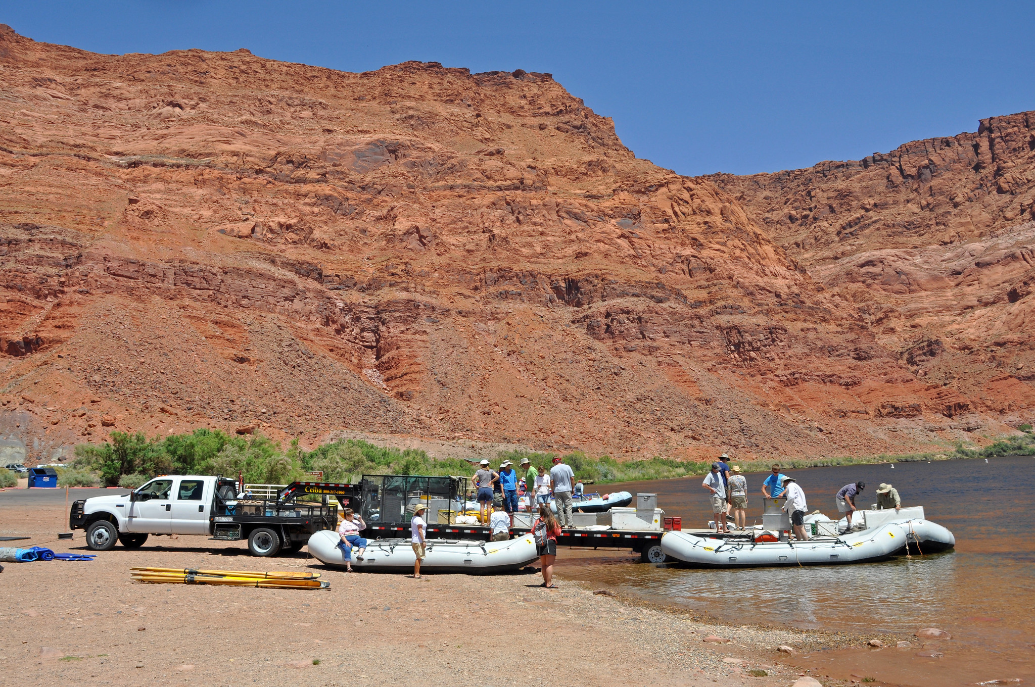 A group of trip participants gather around boats being put into the water at the Lees Ferry boat ramp