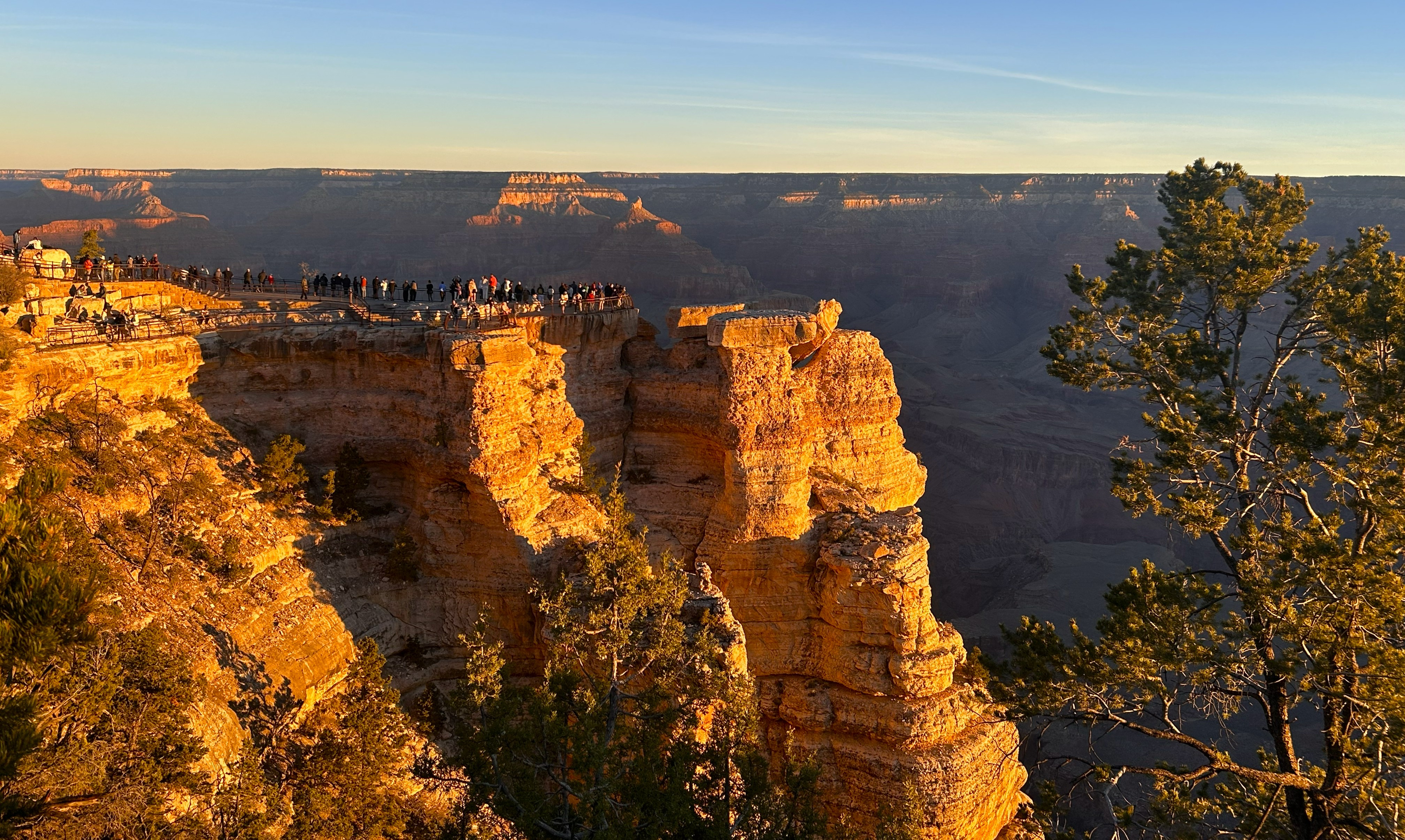 A cliff face with dozens of people standing behind a guardrail
