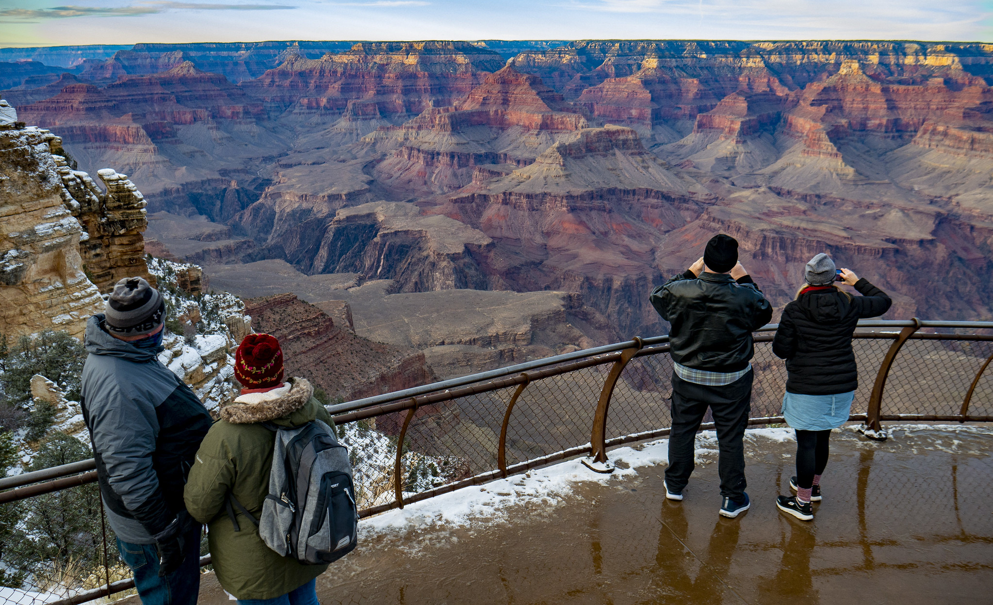 Visitors stand near the railing at Mather Point, looking into the canyon and taking pictures.