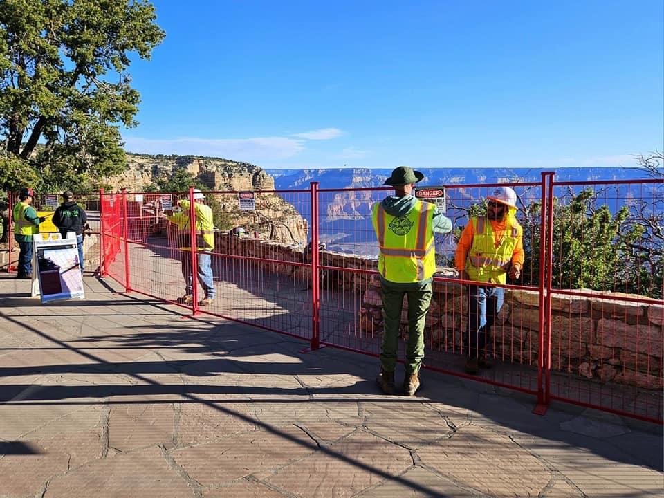 A crew of surveyors looks over the edge of the canyon outside the Bright Angel Lodge