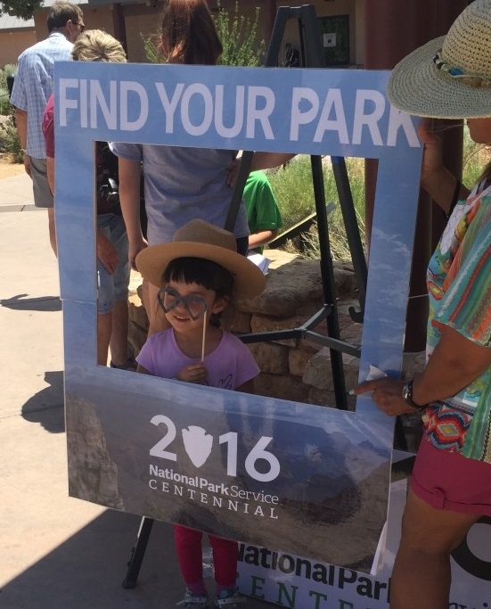 A Grand Canyon Jr. Ranger poses with a Find Your Park sign