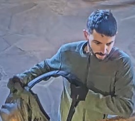 A man is holding a backpack near a desk