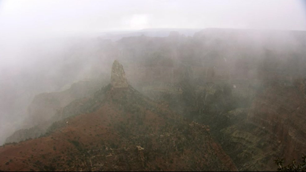 An inner canyon peak is barely visible through fog and snow