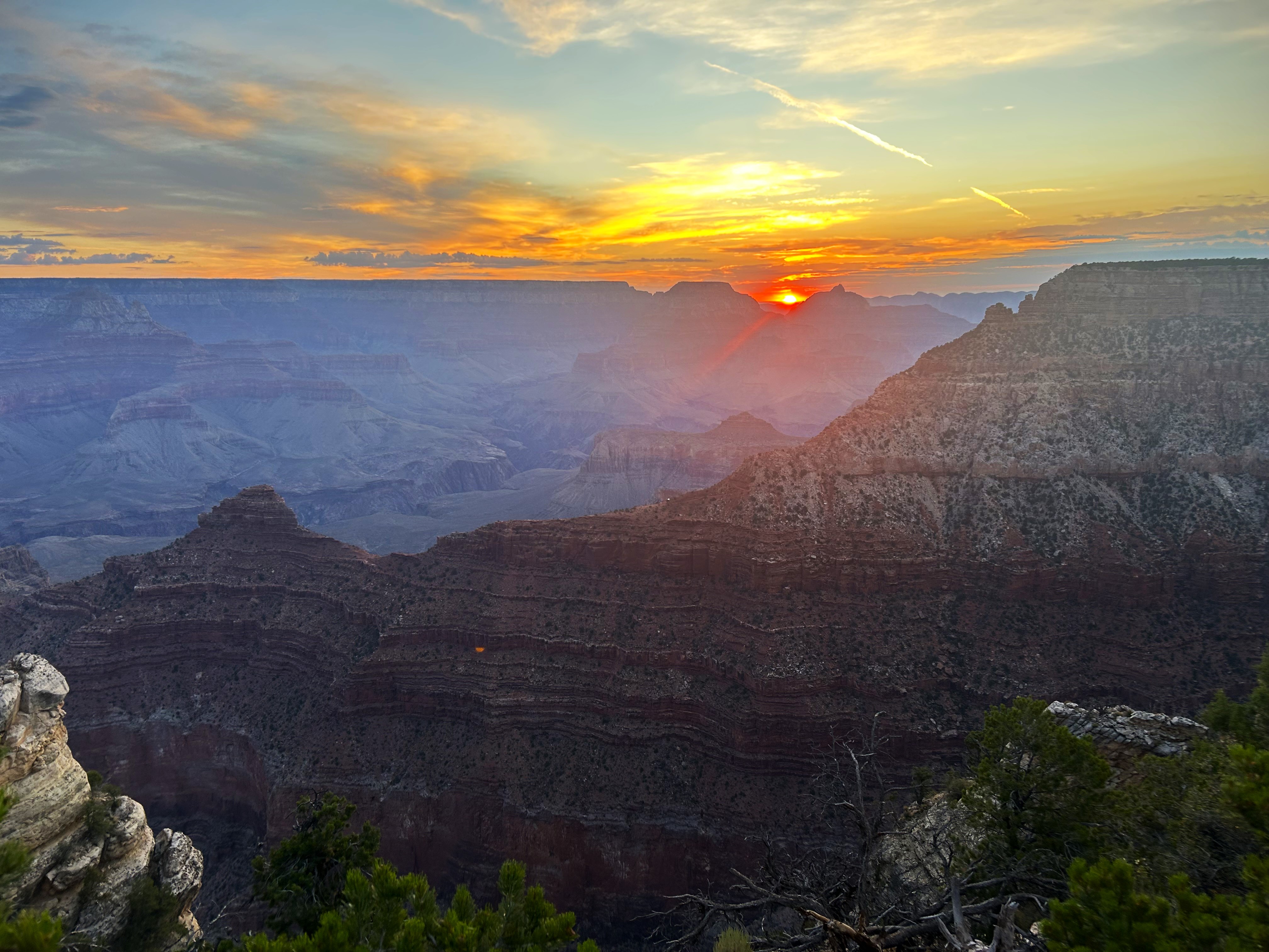 A sunrise with an orange sun on a canyon landscape