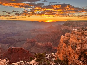 A pink and orange sunrise glow across steep canyon cliffs