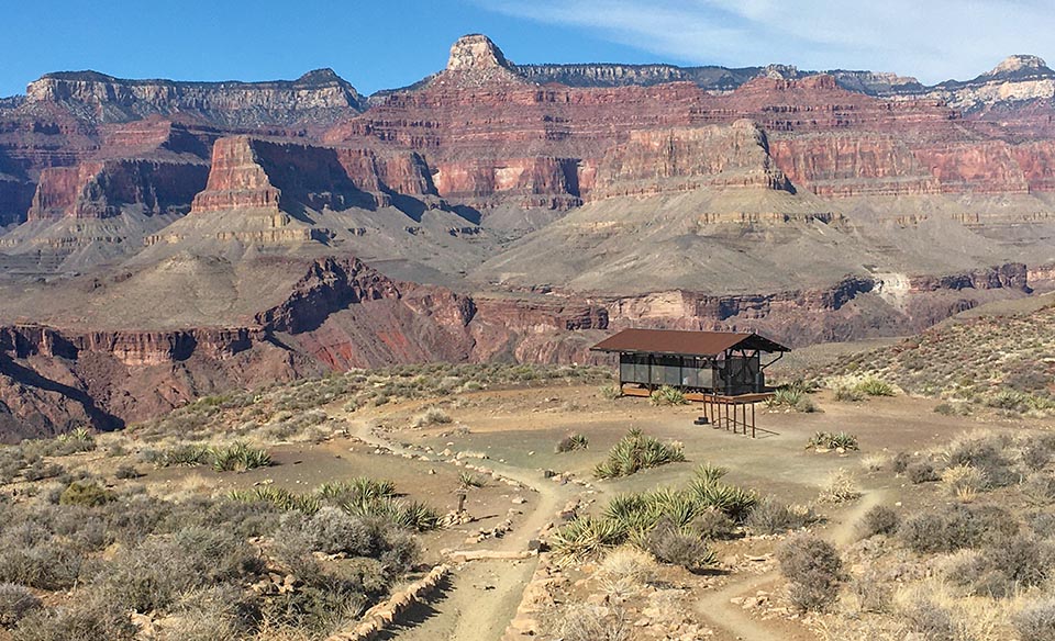 The South Kaibab trail curves to the left of the Tipoff resthouse, which overlooks the edge of the canyon.