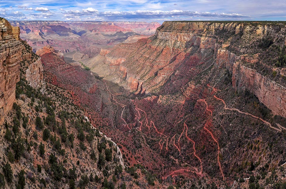 View from First Trailview on the scenic and historic Hermit Road. Looking down, past sheer cliffs several thousand feet, as a trail switchbacks into the depths of a colorful canyon landscape.