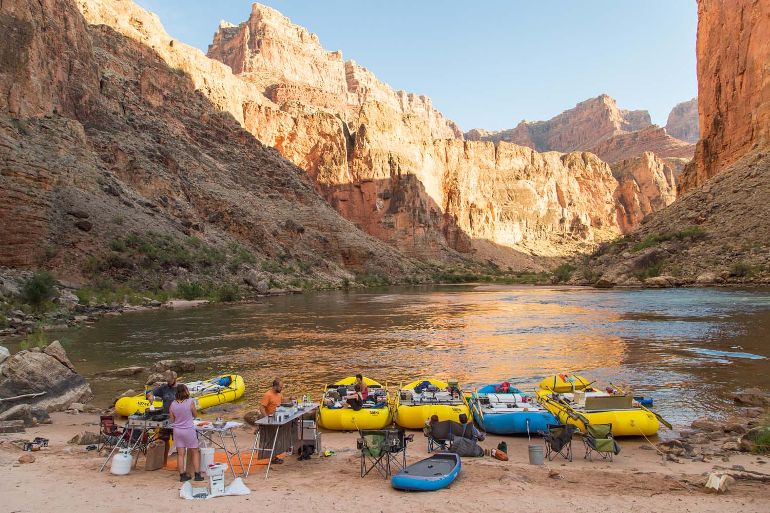 A meal on the beach A group of river runners stand near the edge of the colorado river making a meal together at a river camp