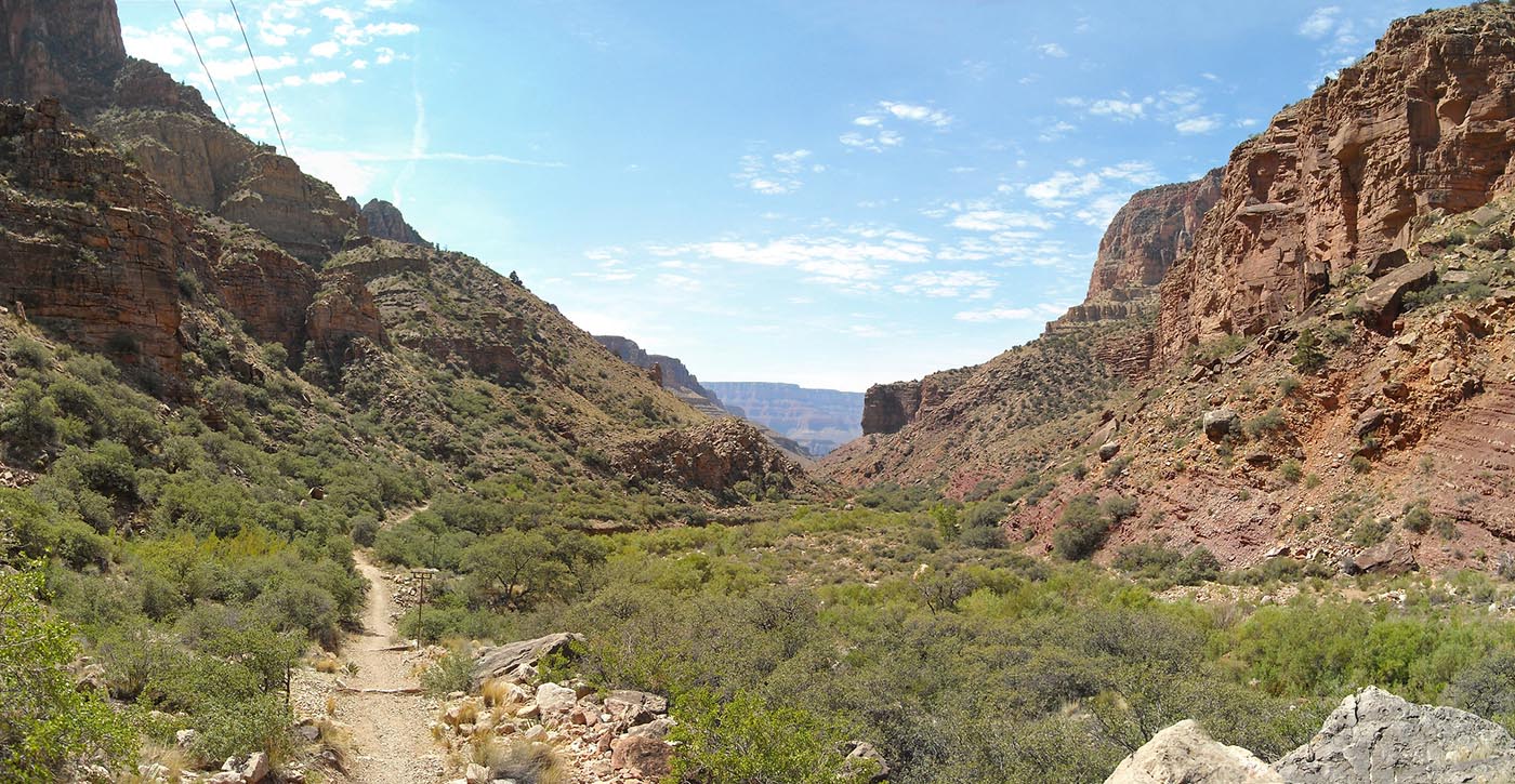 on the left, a backcountry trail is passing through a desert landscape with cliffs on both sides