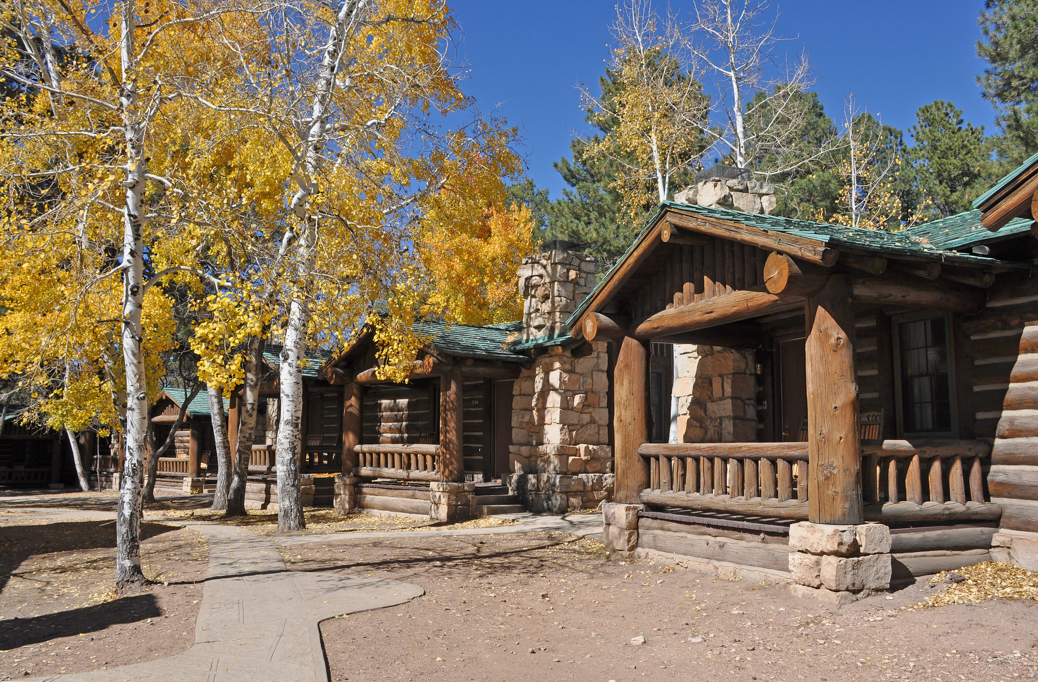 Grand Canyon Lodge on the North Rim several rustic log and stone lodge buildings surrounded by aspen trees with brilliant yellow leaves.