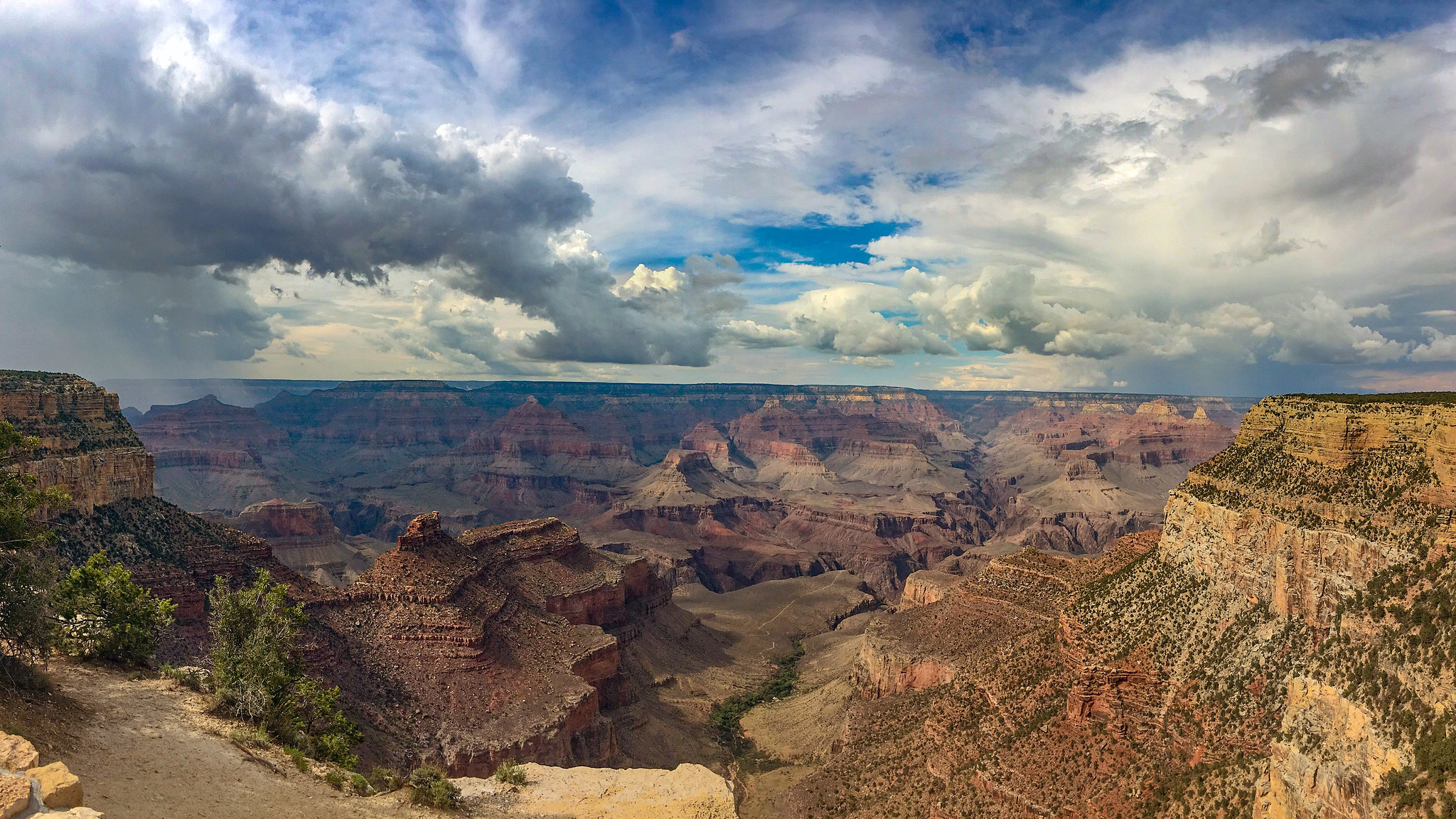 Summer showers - as seem from near Verkamp's Visitor Center in Grand Canyon Village summer monsoon clouds fill the sky above a vast canyon landscape filled with colorful peaks and cliffs.