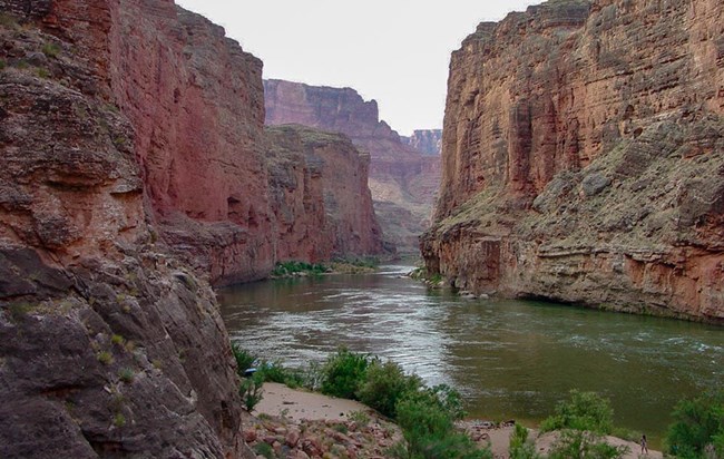 a green river flowing between vertical stone walls within a canyon.