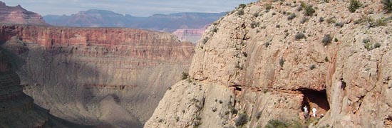 Hikers standing in the entrance to the Cave of the Domes with canyon beyond.