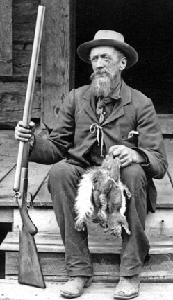 Capt. John Hance sitting on the steps with his rifle and 2 dead squirrels.