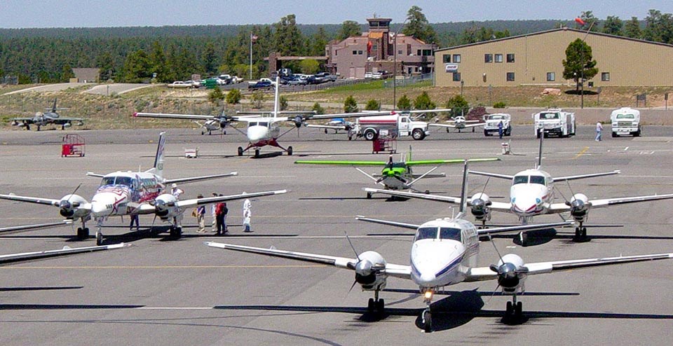 Several white, twin-engine propeller planes on the tarmac at Grand Canyon Airport