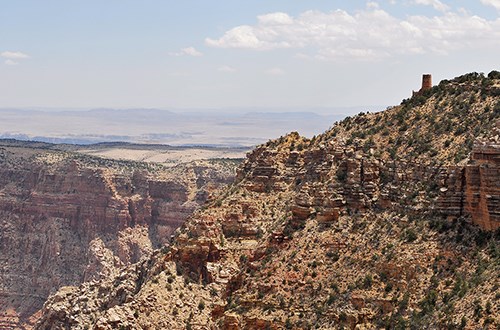 Large cliff goes out into the canyon with a tower at the end.