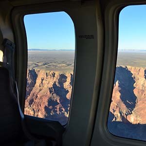View out two window of a tour aircraft at Grand Canyon. Vermilion colored cliffs are visible.