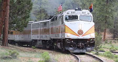 diesel locomotive with red and yellow trim is pulling a passenger train around a curved section of track.