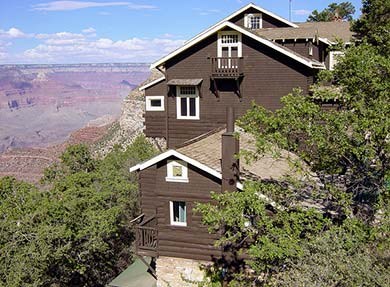 Looking past green oak trees at the west-facing side of Kolb Studio, several storied high, painted brown with white window frames. Grand Canyon is visible on the left and in the distance. Looking past green oak trees at the west-facing side of Kolb Studio, several storied high, painted brown with white window frames. Grand Canyon is visible on the left and in the distance.