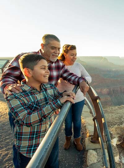 A family viewing the Grand Canyon safely from behind the railing at an overlook.