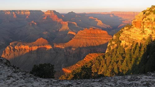 From a limestone ledge, looking out across the landscape as the last light of day illuminates peaks and ridgelines.