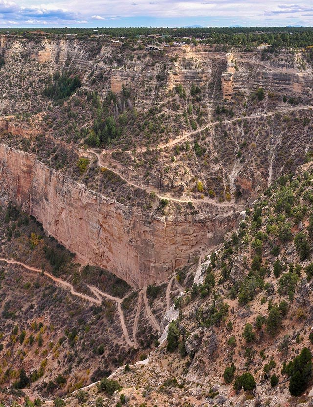 a backcountry trail descends thousands of feet through slopes and around sheer cliffs that make up the walls of a vast canyon. NPS/M. Quinn