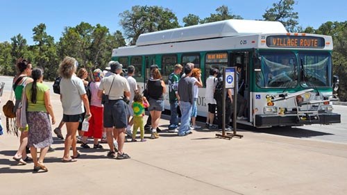 Village Loop Bus at Transit Center a line of people boarding a green and white bus.