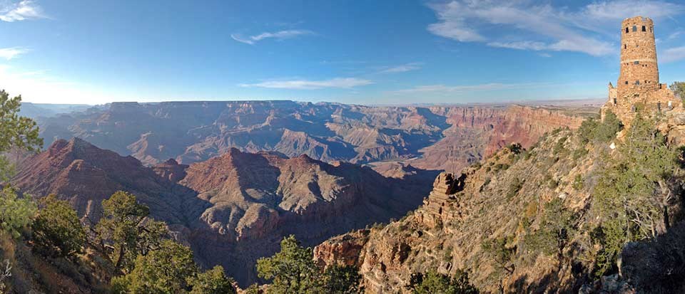 An expansive view of Grand Canyon from Desert View with the Watchtower in the upper left, perched on the edge of a cliff