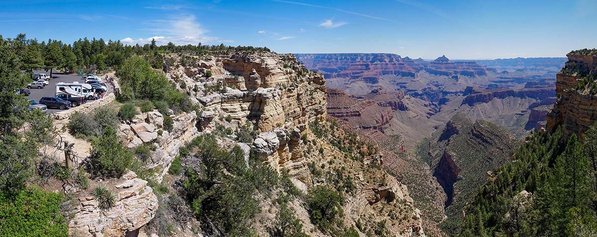 This is the pullout at Duck on a Rock overlook, along Desert View Drive. Beyond an almost sheer cliff, and immense canyon is visible in the distance, with colorful peaks and buttes. NPS photo.