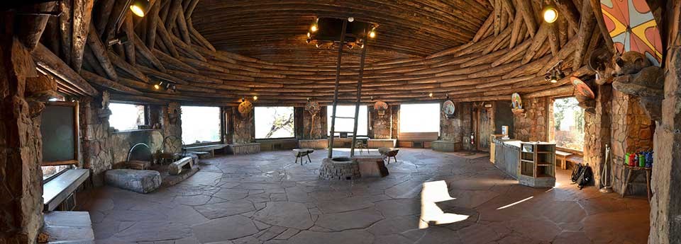 looking acros round Kiva Room of Watchtower. Large picture windows around the circumfrence alternate with stone pillars that hold up a circular log roof. Flagstone floor. In the center, a primitive ladder that goes from floor to ceiling.