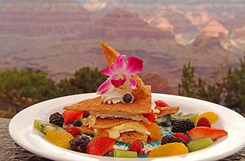 Dessert on a plate that includes triangular shaped pastry wedges that are surrounded by a variety of fresh fruit.