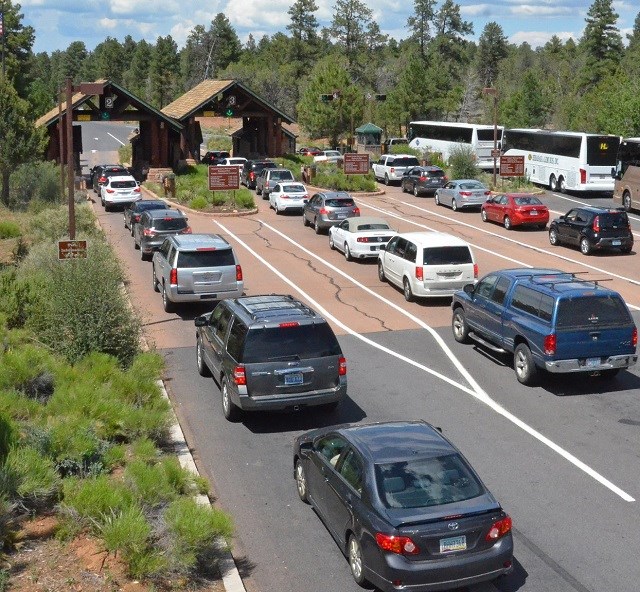 four lines of cars and buses waiting to enter the park at an entrance station