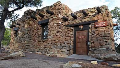 front of Tusayan Museum, a small mostly stone building with log vigas and lentils. NPS Arrowhead above front door.