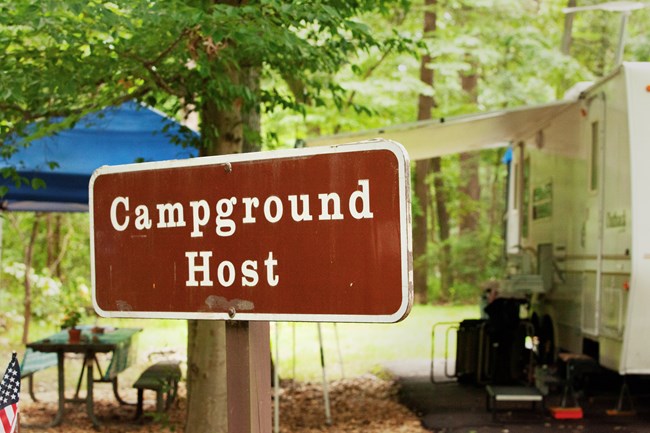 Campground host sign in front of a camper.