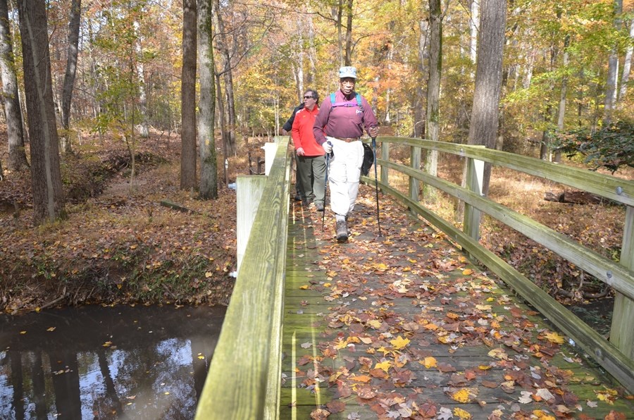 three people walking across the bridge in Greenbelt Park, Maryland