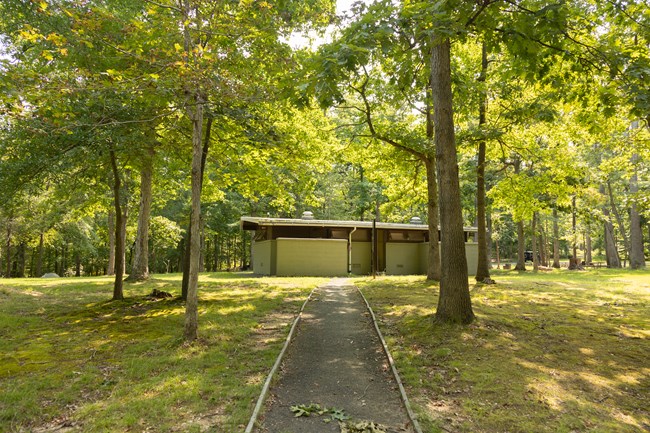 A paved road with curbing leads to a campground comfort station