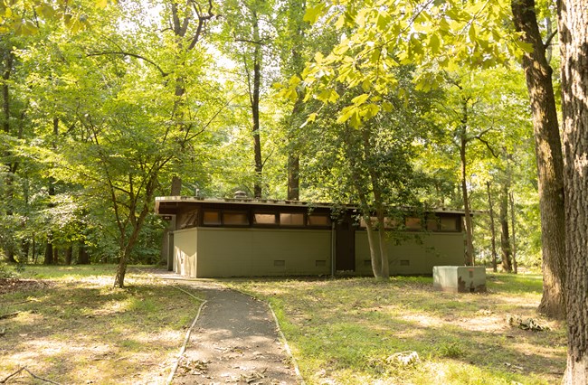 A paved path with curbing leads to a campground comfort station