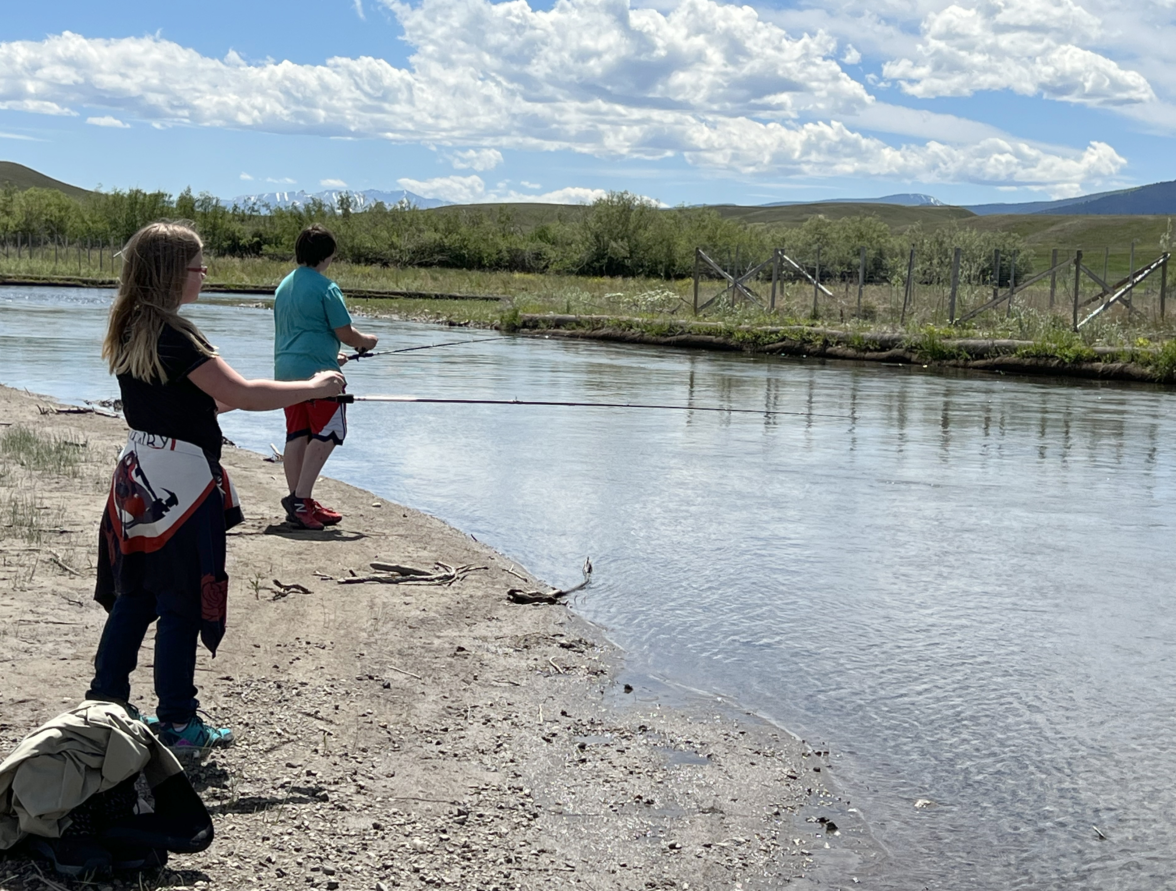 Two girls fishing along the bank of the river