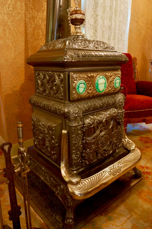 Kohrs' ornate wood burning stove with inlaid acorn tiles in silver colored stove.