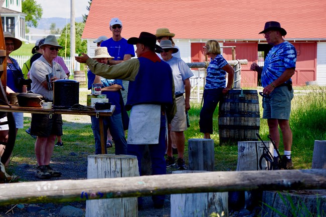 crowd of visitors surround ranger in historic cowboy clothes at chuckwagon