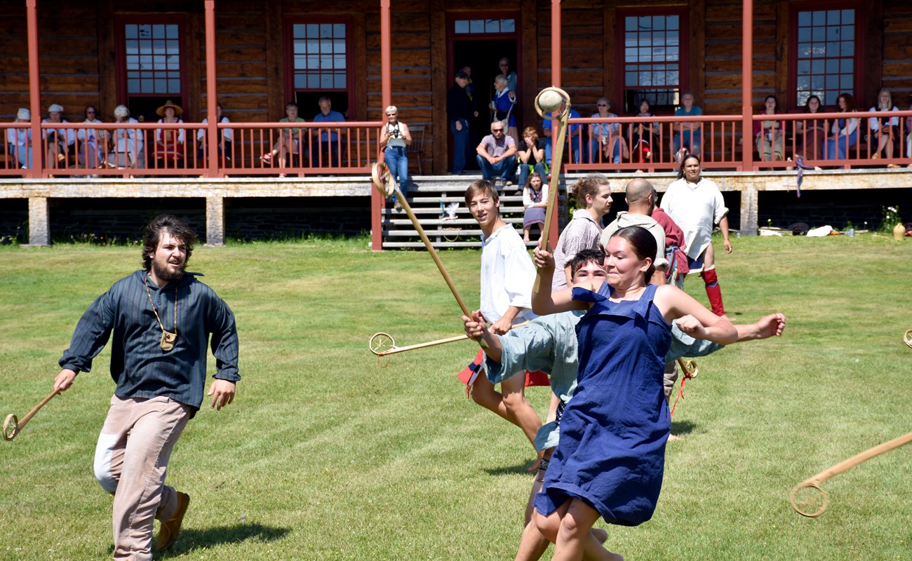 Action shot of a lacrosse game in front of a historic building.